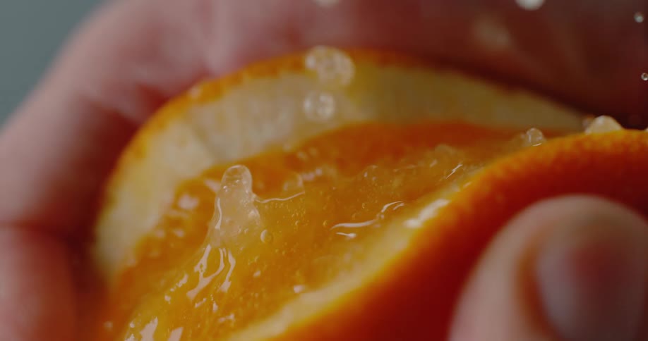 Close up of an orange bursting while being squeezed