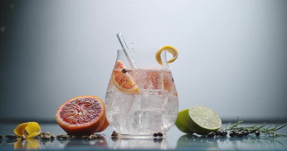 A drink being poured into a cocktail glass garnished with citrus