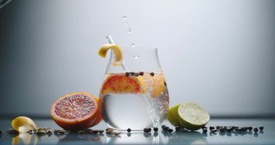 Clear crystal water pouring over ice cubes in a cocktail inside a glass or goblet