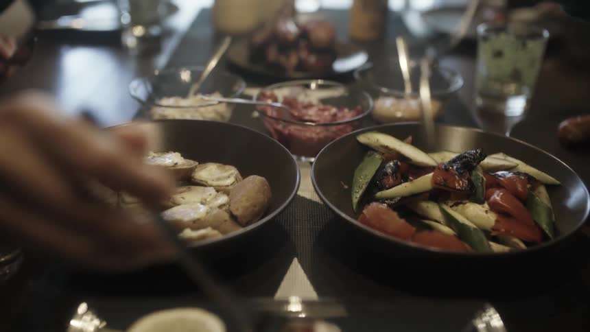 People are sitting down to a meal serving themselves from dishes