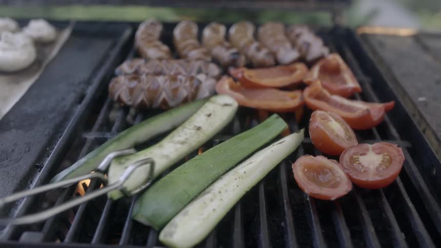 Veggies and sausages being cooked on a grill