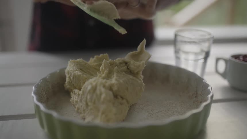 A batter is pushed from a spatula into a prepared baking dish