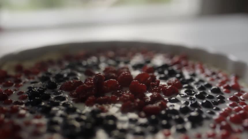 A person is putting berries on a pie