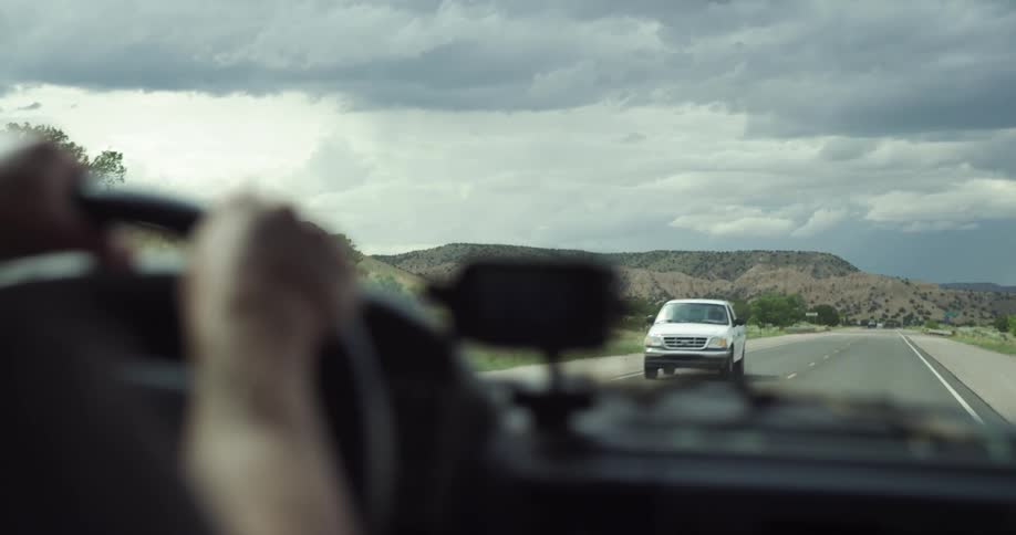 A person driving a car down a road in the desert