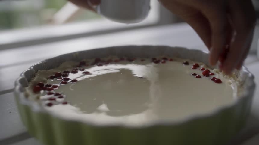 A person places berries on top of a custard