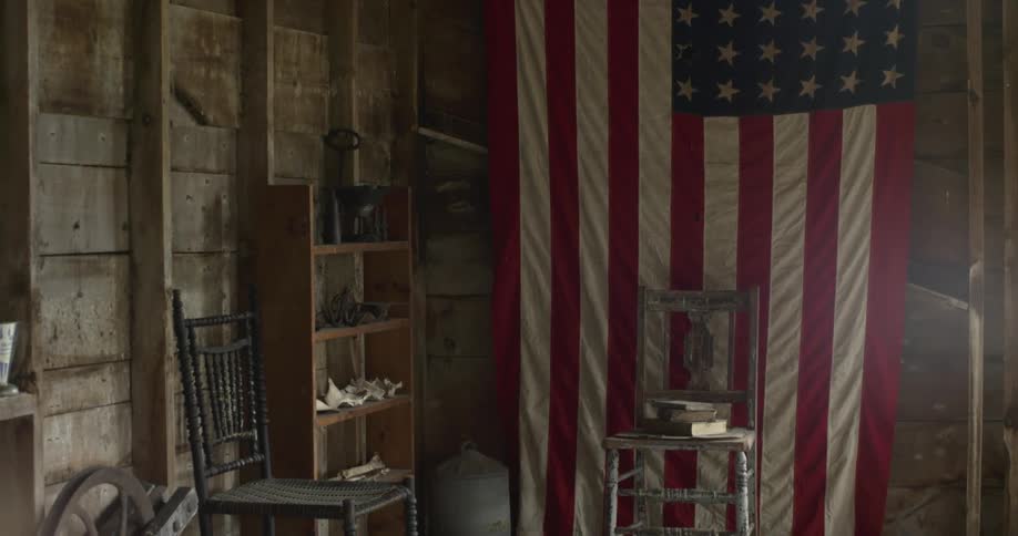 An american flag hangs from a wooden wall in a building during the day