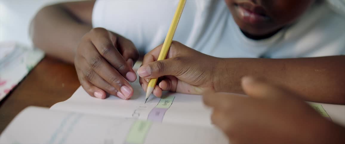 Two young boys doing homework with pencil and paper at home