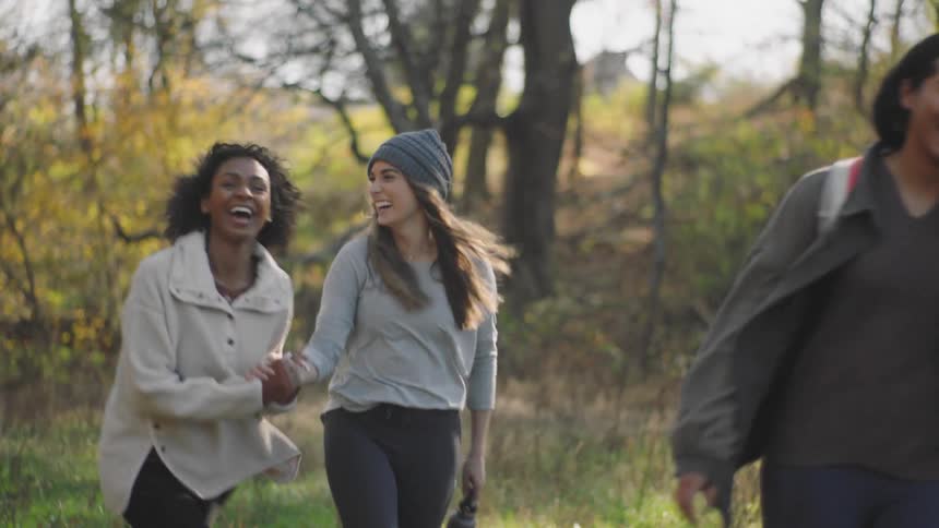 Three woman walking and laughing with trees the sky and clouds in the background