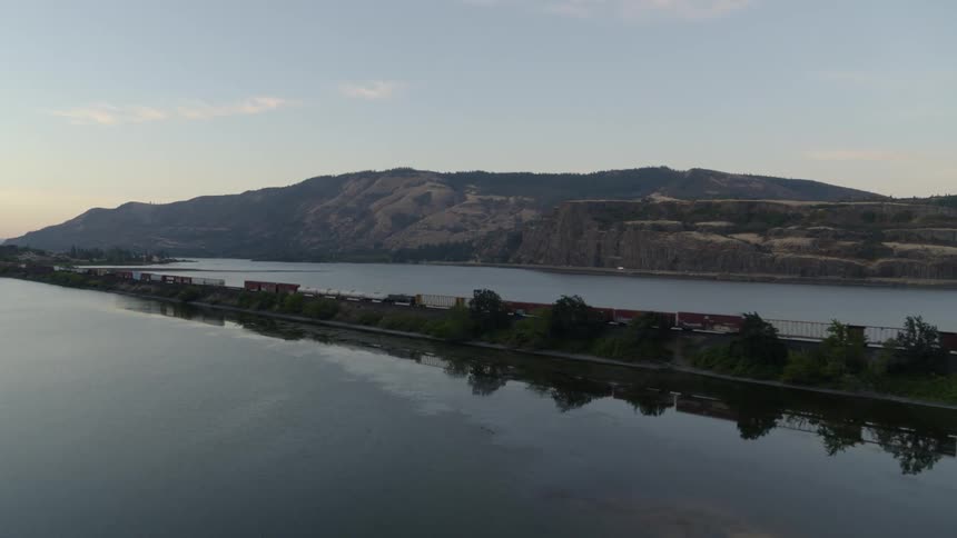 Orbit around a fast moving freight train traveling along a causeway through a calm lake