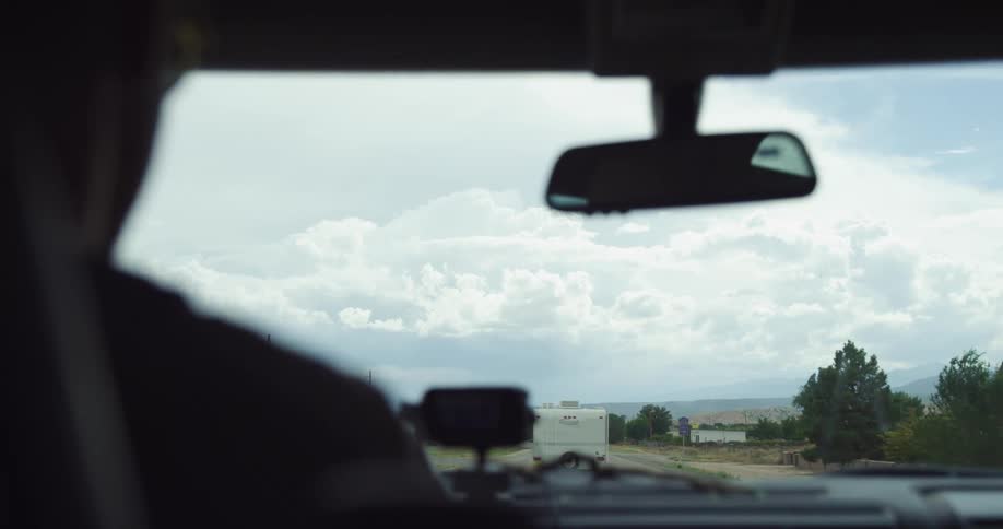 Interior view from car driving along countryside while following a travel trailer