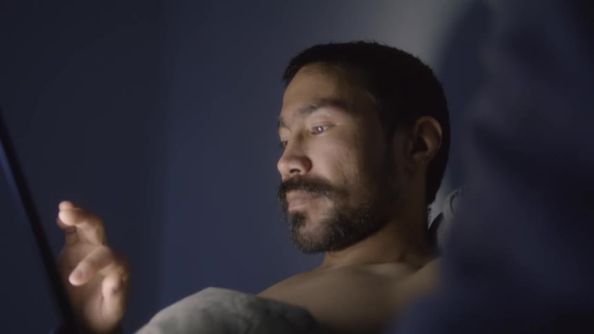 A man is using a tablet indoors at night