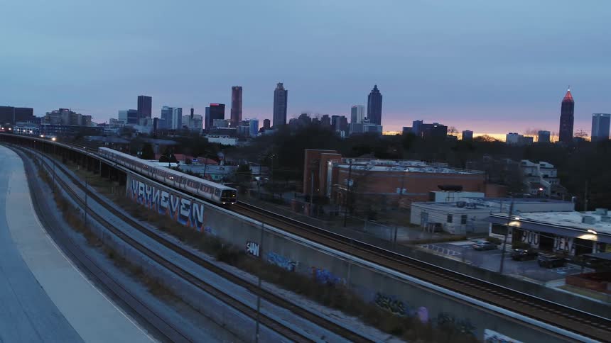 Train moving over the gracks near the city skyline at sunset