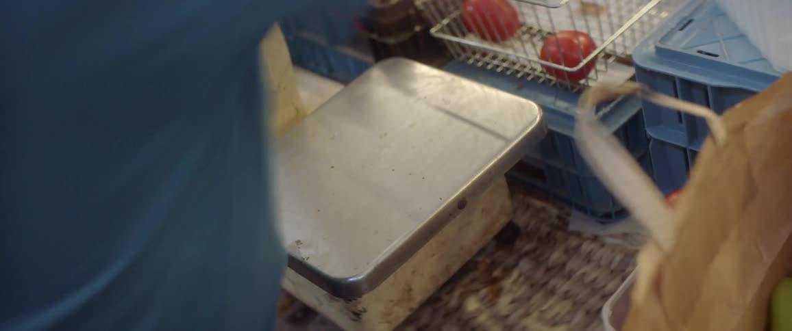 A man weighing fruits and vegetables on a metal scale