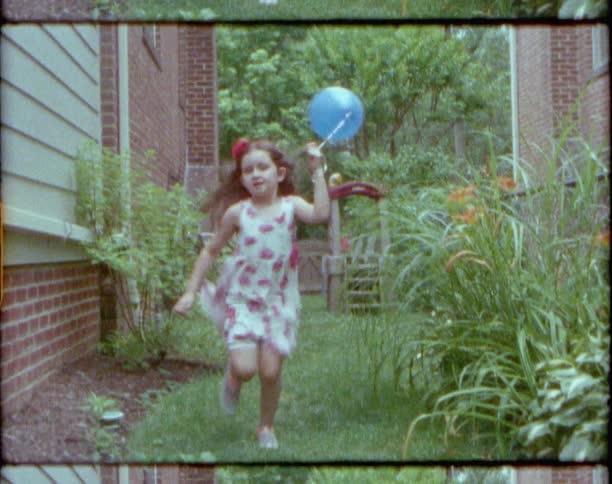 A young girl runs outside houses with a balloon