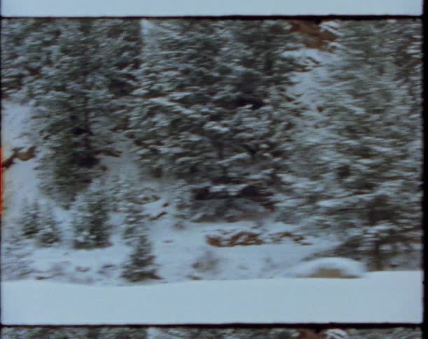Traveling past a home at the base of a snow and tree covered slope