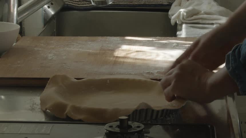 A man placing pie dough over a pan in the kitchen counter top at home