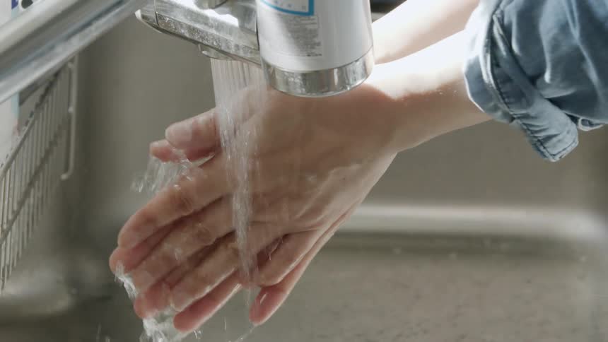 A person is washing their hands under a faucet