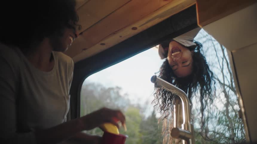 A girl hangs over the window frightening the women inside and they laugh
