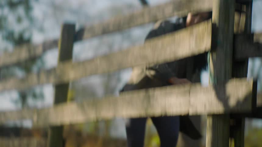 Two women crawl under the farm fence