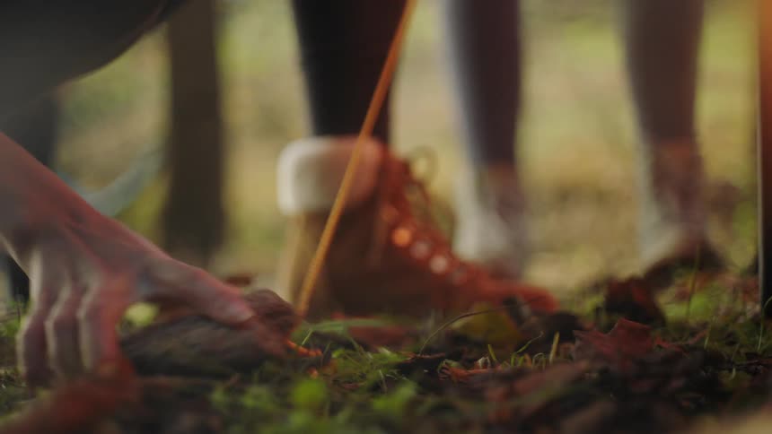 Person wearing hiking boots pounds tent stake into ground