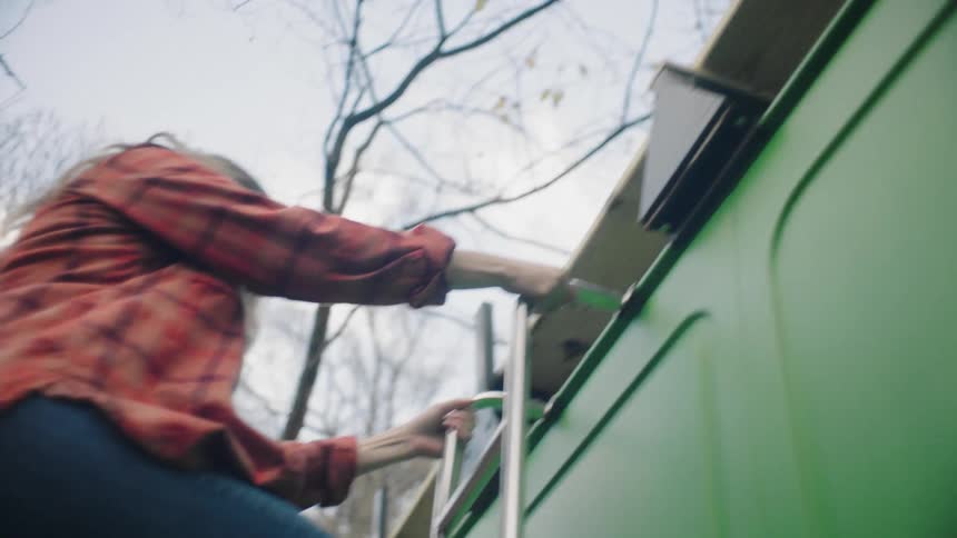 A woman climbing down a ladder on a vehicle