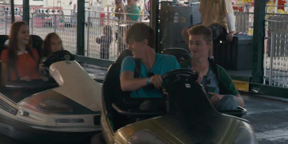 A pair of men in a bumper car crash into another car before being crashed into from behind