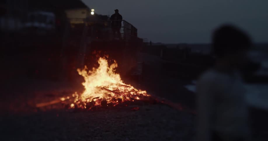 Flames from the bonfire burn brightly in the darkness