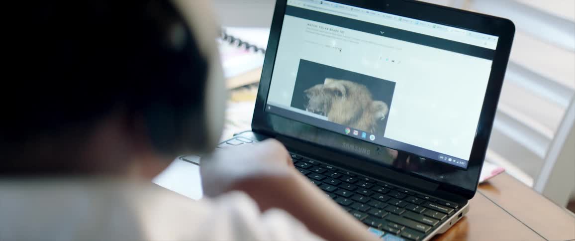 Young boy wearing headphones doing homework at home with a laptop
