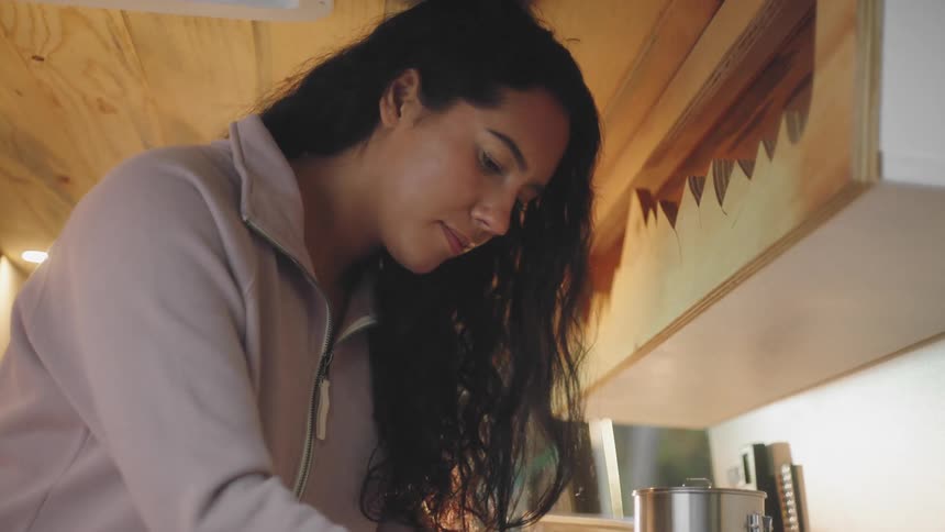 A woman looks down as she turns a handle round and round