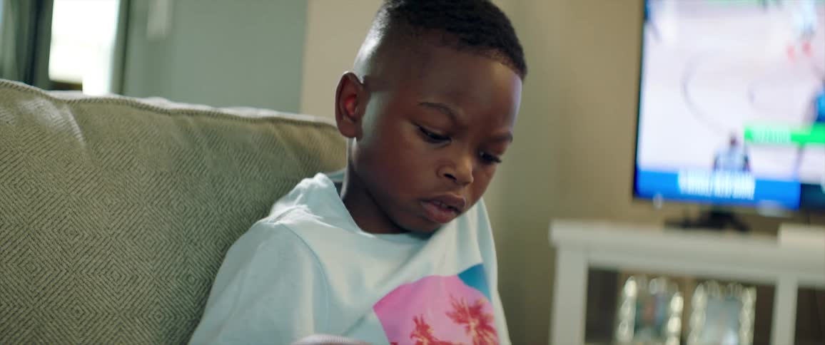 Young boy sitting in a couch inside the living room at home reads a book