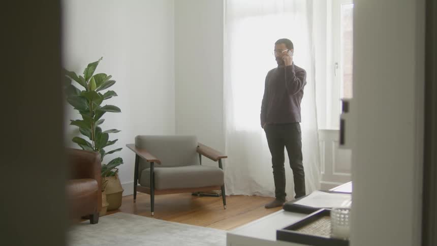 A man is talking on a cell phone indoors