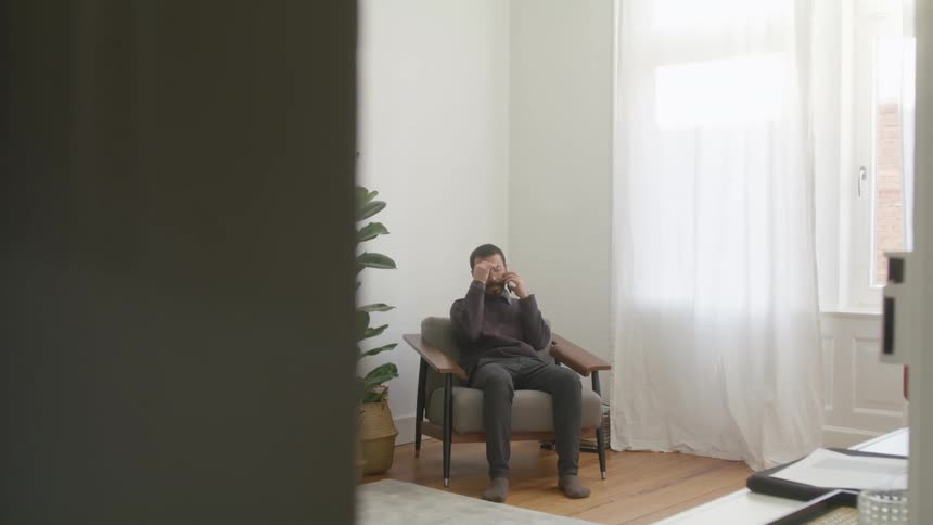 A man is walking around a room while talking on a cellphone