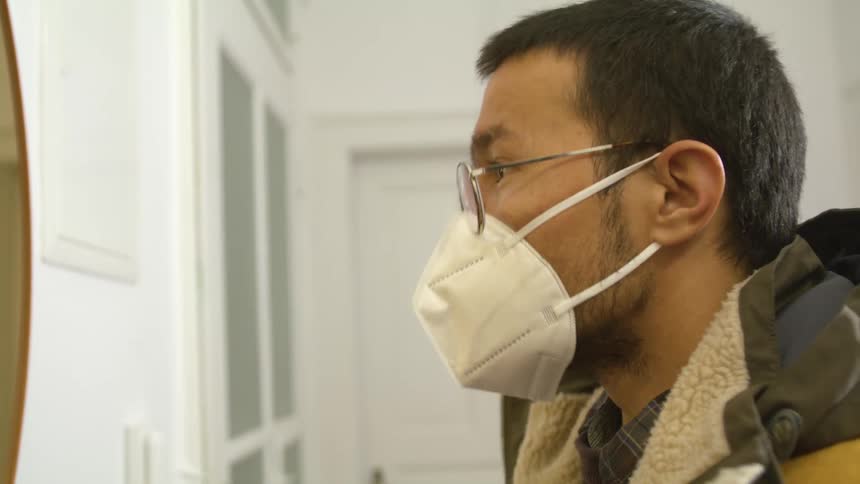 Man puts on face mask before leaving home