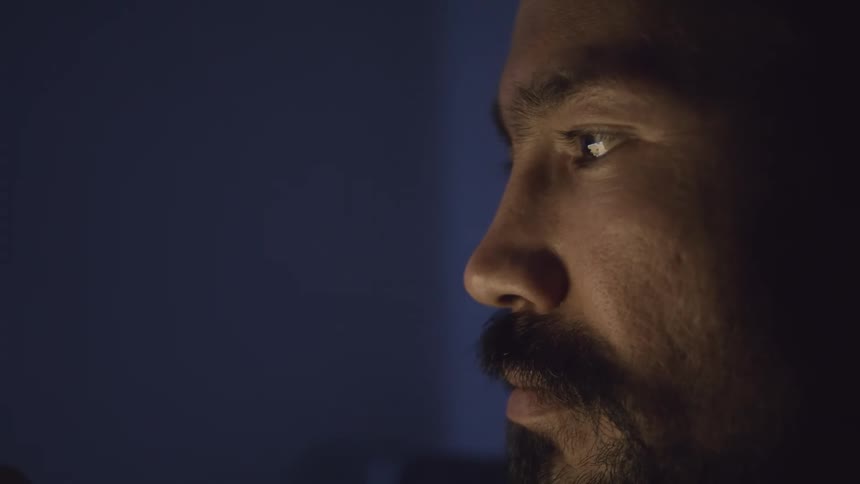 A mans face in profile with dim light shining on him
