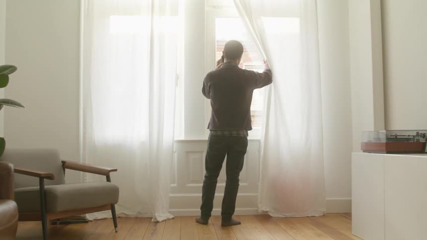 Man talking on mobile phone looks out window