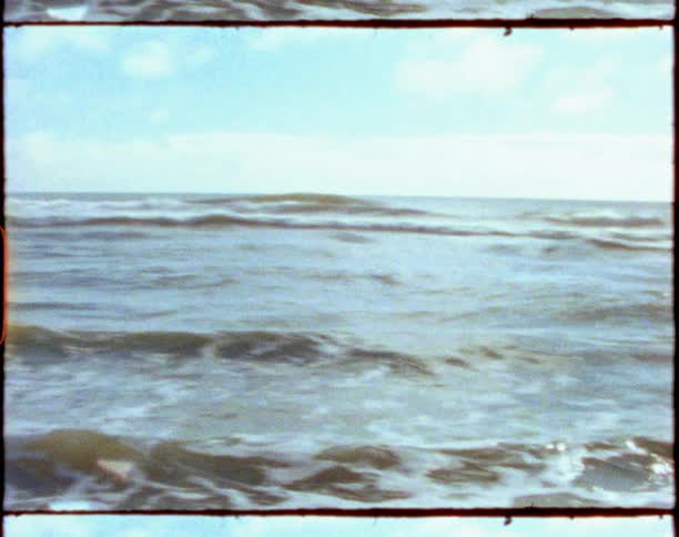 Footage of an ocean and beach is displayed during the day