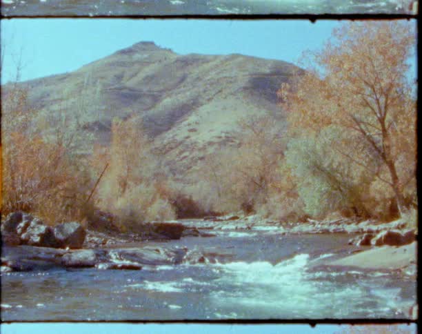 A river with trees a mountain range the sky and clouds in the background