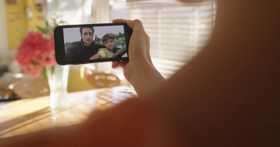 Person sitting at table video calls with father and son enjoying themselves outdoors