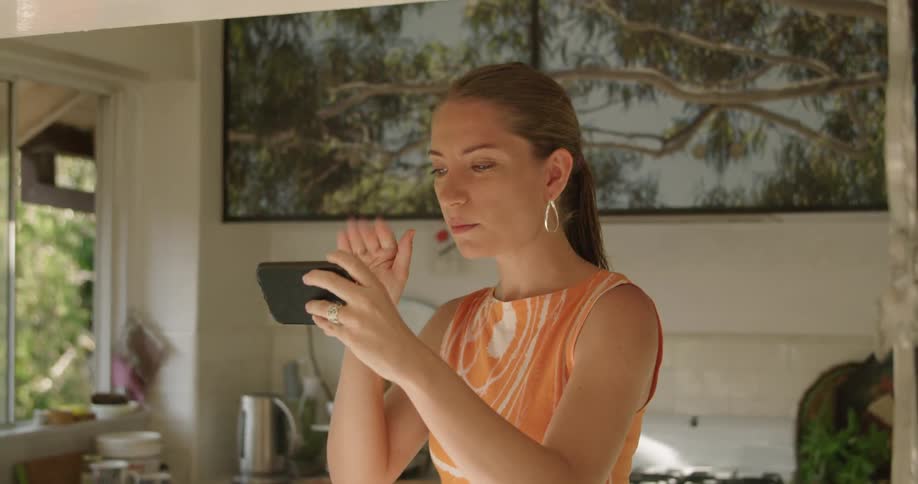 A woman waving and blowing kisses during a video chat on a smartphone
