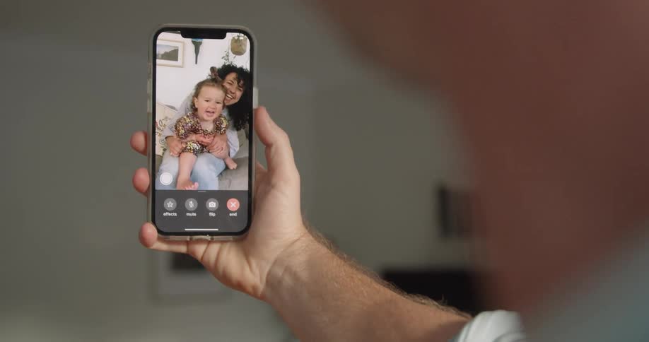 A man video chatting with a happy woman and baby on a smartphone