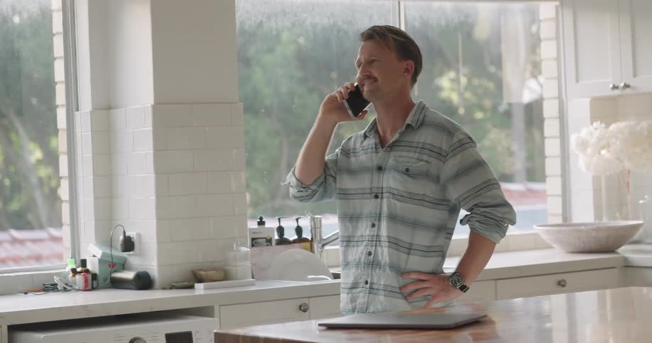 A man talking on a cell phone in a kitchen