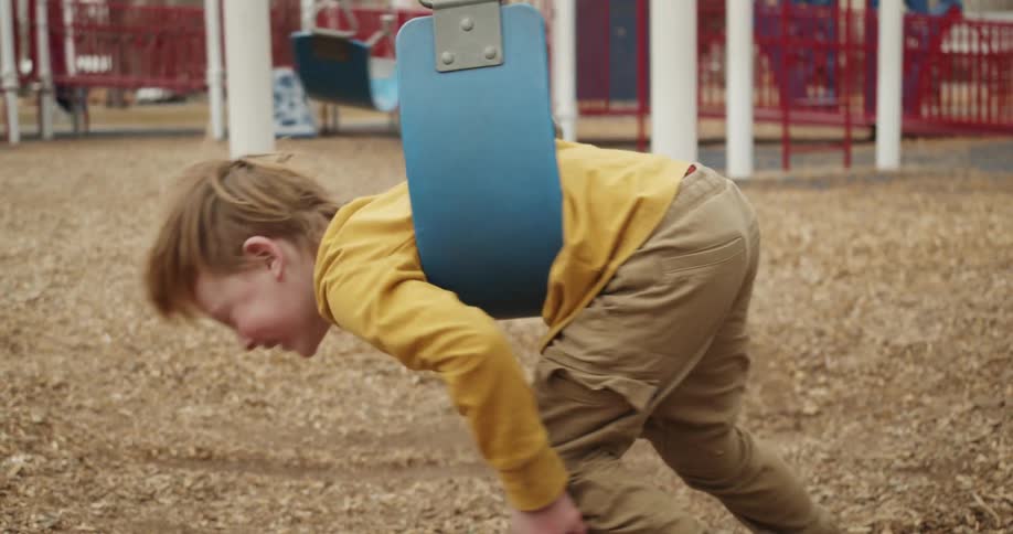 A child is playing at the park on a swing