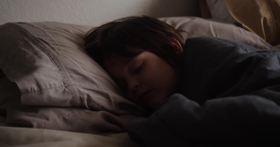 A person laying on a bed and sleeping with a blanket and pillow