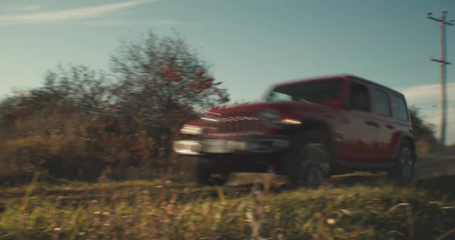 A vehicle drives quickly down a road next to a field