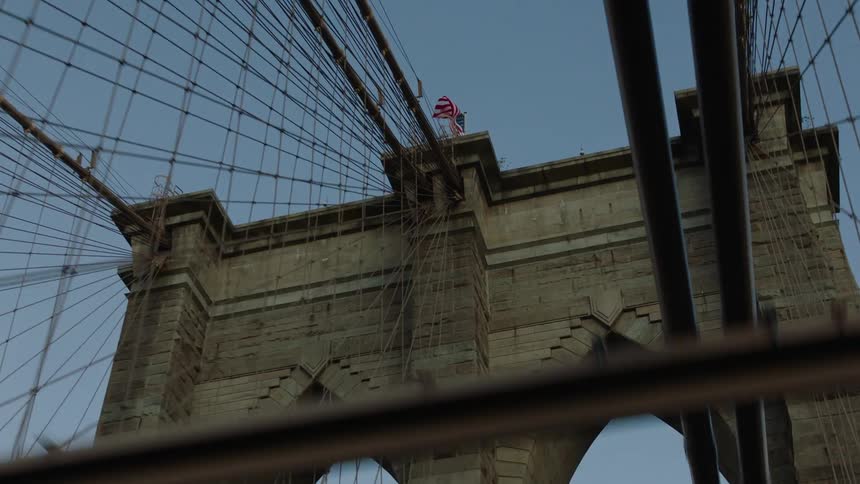 An american flag flies on the top of a bridge suspender