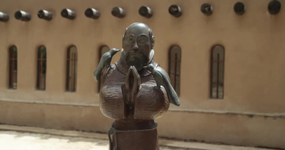 A statue is outside a building during midday