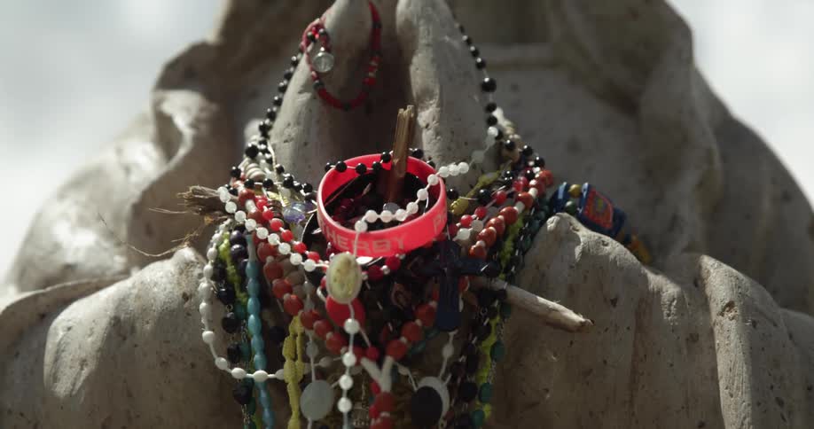 Beads draped around the hands of an outdoor monument during the day