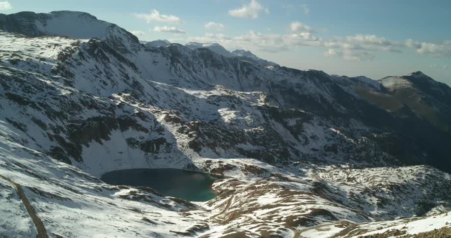 A mountain range covered in ice and snow with the sky and clouds in the background