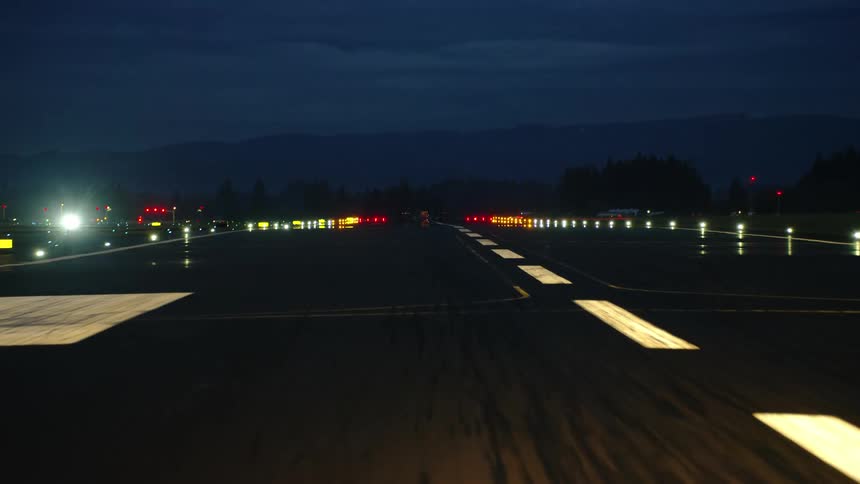 Awesome pilot POV aerial shot of a night shot landing at an airport at night with blue light in the background