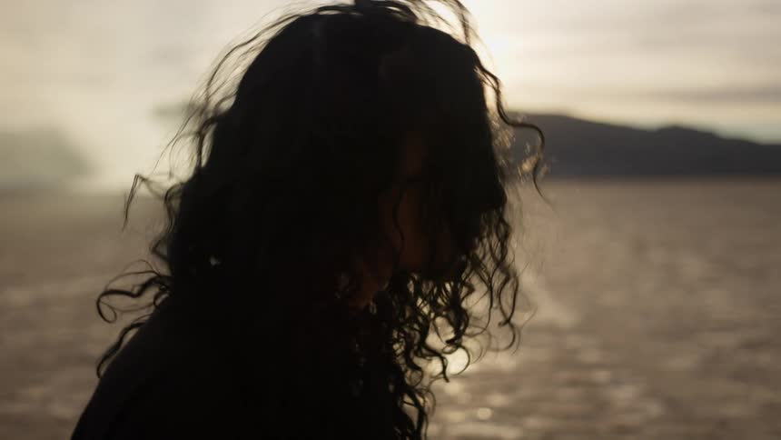 The silhouette of a woman dropping her head as the desert sun glares down on her